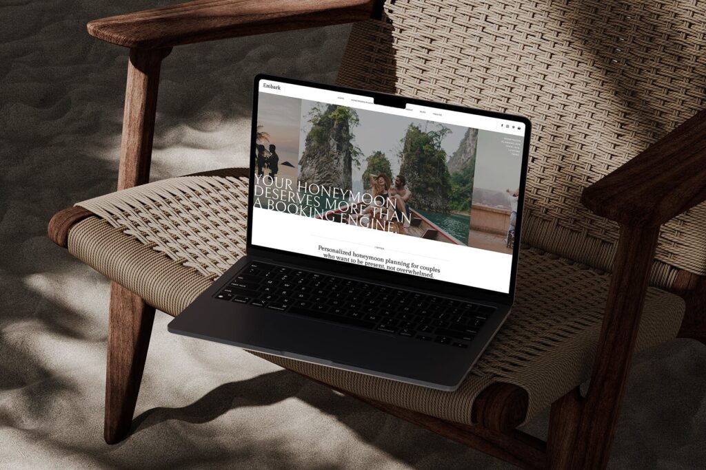 A laptop in a woven chair on sand, with a honeymoon travel advisor website pulled up on the screen