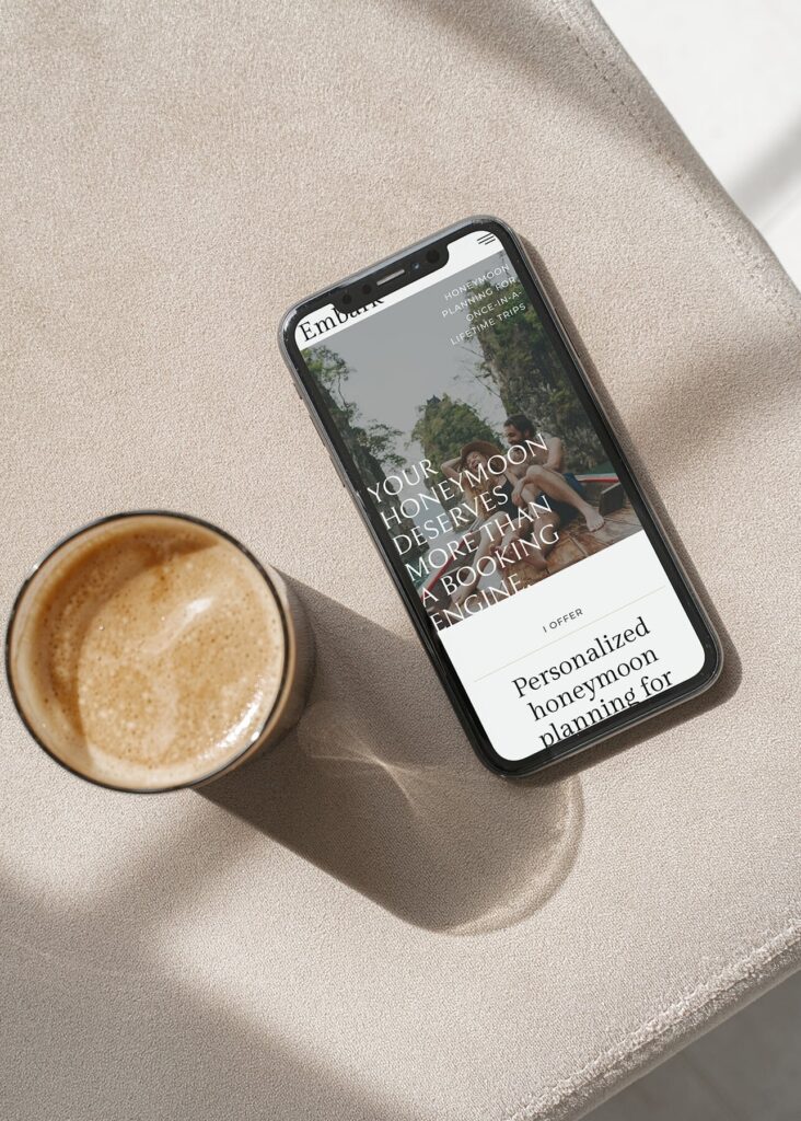 Phone & coffee on an ottoman with a travel advisor website on screen