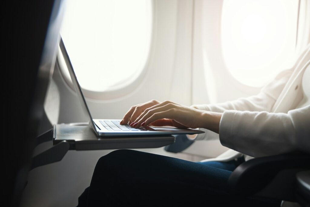 Close up of a travel advisor on her laptop on a flight setting up Google Business Profile